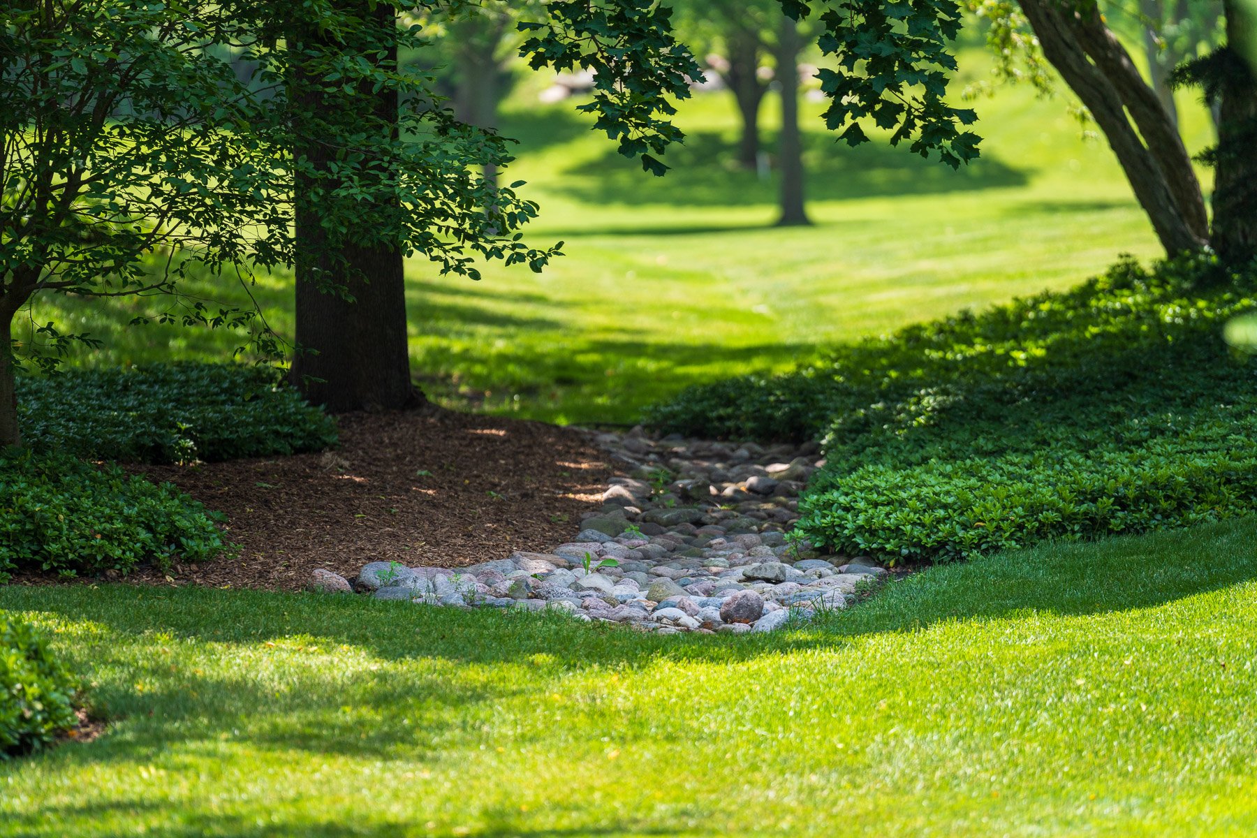 dry creek through landscape beds green lawn